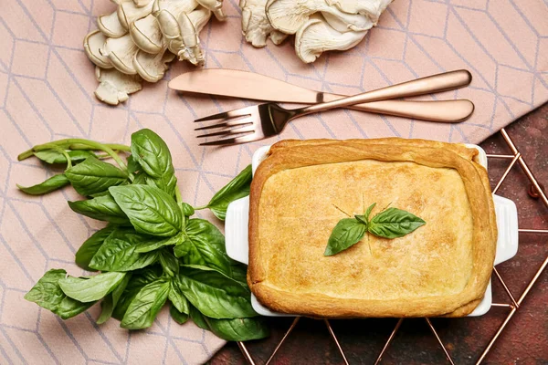 Lezzetli mantarlı turta ve arkaplandaki malzemelerle pişirme yemeği.