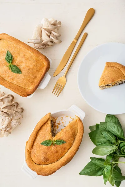 Beyaz ahşap arka planda lezzetli mantarlı tabak ve tabak.