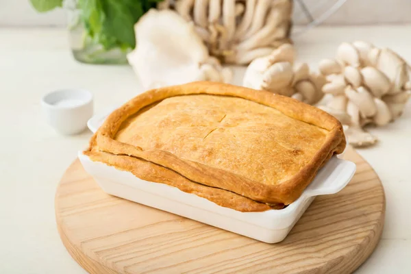 Beyaz ahşap zemin üzerinde lezzetli mantarlı turta pişirme tabağı