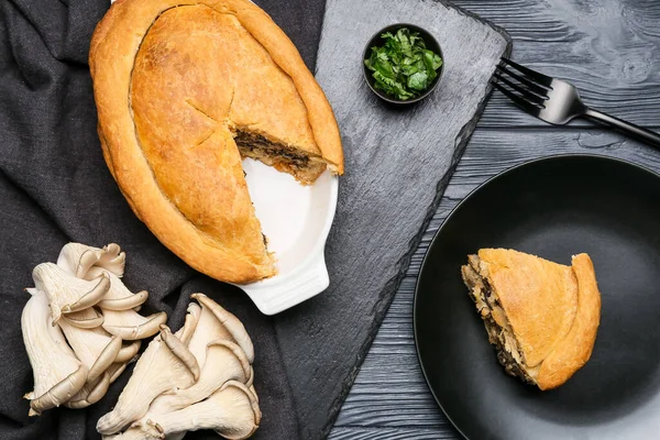 Siyah ahşap arka planda lezzetli mantarlı yemek ve tabak.