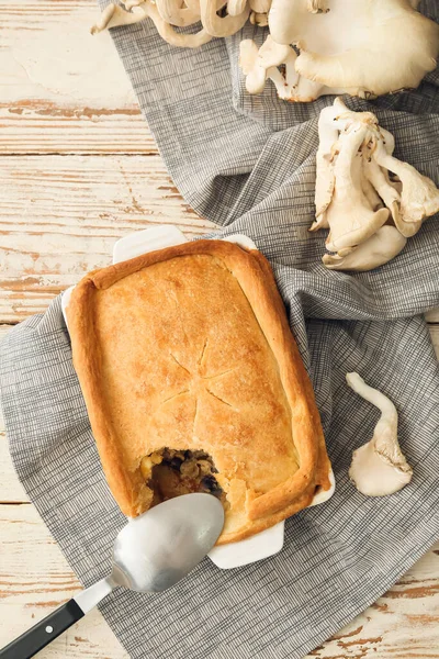 Beyaz ahşap zemin üzerinde lezzetli mantarlı turta pişirme tabağı