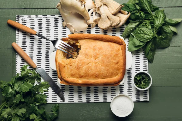 Lezzetli mantarlı fırın yemeği ve yeşil ahşap arka planda malzemeler.