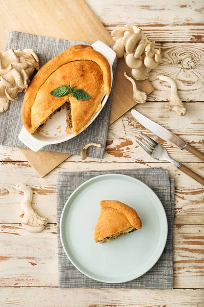 Beyaz ahşap arka planda lezzetli mantarlı yemek ve tabak.