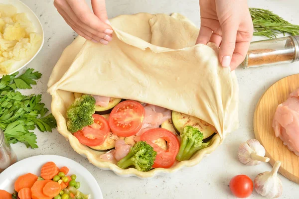 Beyaz arka planda sebzeli tavuk güveci hazırlayan kadın.