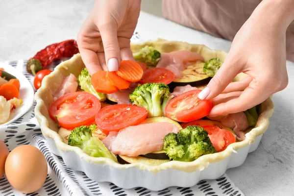 Mutfak masasında sebzeli tavuk güveci hazırlayan kadın.