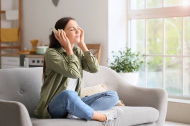 Evde müzik dinleyen güzel genç bir kadın.