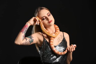 Siyah arka planda yılan olan seksi genç kadın.