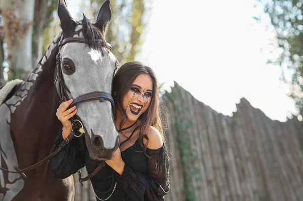 美しい女性は馬とハロウィーンのために服を着てスケルトン屋外 — ストック写真