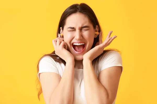 Emotionale Junge Frau Mit Ohrstöpseln Auf Gelbem Hintergrund — Stockfoto