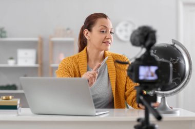 Öğretmen, öğrencileri için evde video kaydı yapıyor.