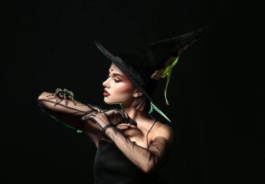 Karanlık arka planda örümceği olan genç cadı