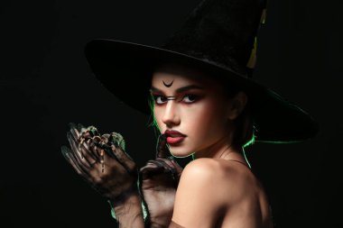 Karanlık arka planda örümceği olan genç cadı