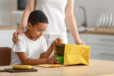 Anne ve küçük oğlu okuldan önce öğle yemeğini çantaya koyuyorlar.