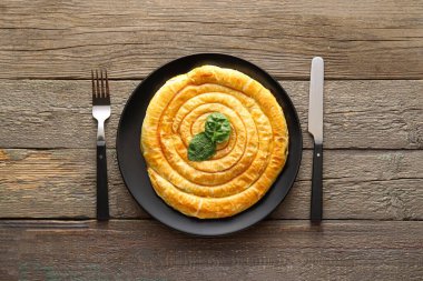 Ahşap zemin üzerinde lezzetli ıspanaklı turta tabağı.