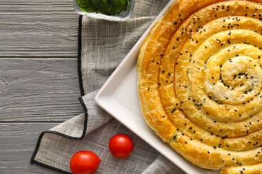 Gri ahşap arka planda lezzetli ıspanaklı turta, yakın plan.
