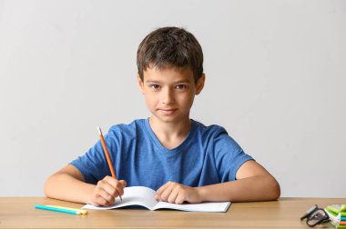 Küçük çocuk masa arkasında ödev yapıyor.