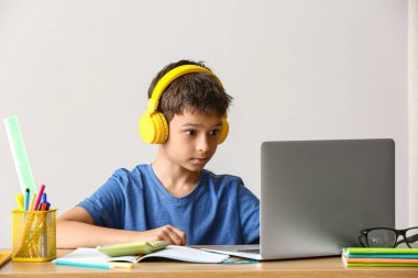 Küçük çocuk açık arkaplanda internette ödev yapıyor.