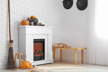 Beyaz tuğla duvarın yanında Cadılar Bayramı dekorlu modern şömine