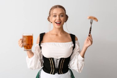 Geleneksel Alman kostümlü güzel bir kadın, sosis ve gri arka planda bir kupa birayla.