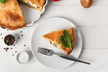 Beyaz ahşap arka planda lezzetli bir tavuklu turta ile yemek pişirme tabağı