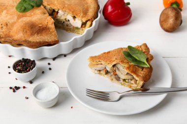 Beyaz ahşap arka planda lezzetli bir tavuklu turta ile yemek pişirme tabağı