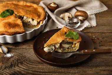 Ahşap arka planda lezzetli bir tavuklu turta ile fırın tabağı.