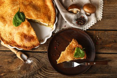 Ahşap arka planda lezzetli bir tavuklu turta ile fırın tabağı.