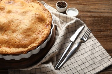 Ahşap arka planda lezzetli tavuklu turta pişirme tabağı, yakın plan.