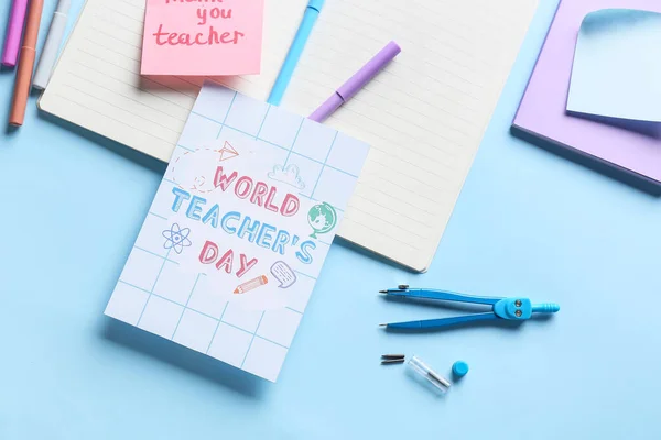 Concept of Teacher\'s Day. School supplies and greeting card on blue background, top view