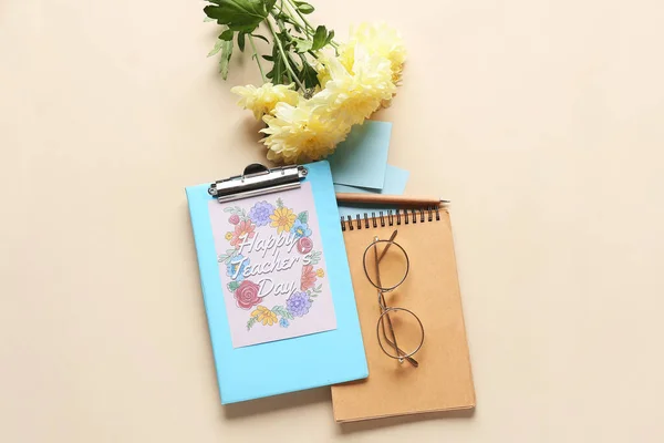 Teacher's Day celebration. Greeting card, glasses, notebook and flowers on beige background, top view