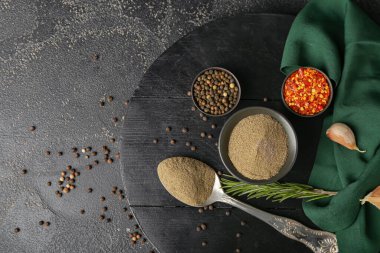 Koyu arkaplanda siyah biber tozu olan kase ve kaşık.
