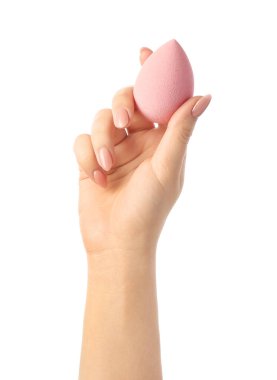 Beyaz arka planda pembe makyaj süngeri olan bir kadın eli.