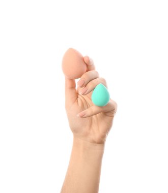 Beyaz arka planda şık makyaj süngerleri olan kadın eli.