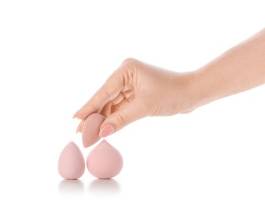 Beyaz arka planda şık makyaj süngerleri olan kadın eli.