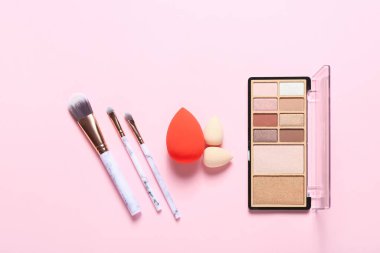 Renkli arka planda şık makyaj süngerleri ve dekoratif kozmetikler