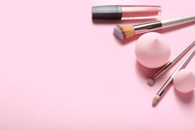 Renkli arka planda şık makyaj süngerleri, ruj ve fırçalar