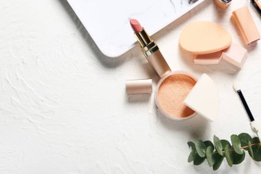Hafif arkaplanda şık makyaj süngerleri ve dekoratif kozmetik ürünleri