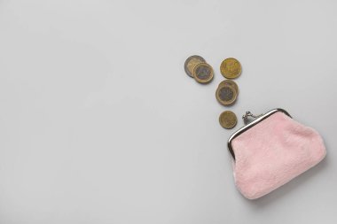 Açık arkaplanda bozuk para olan pembe cüzdan.