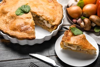 Siyah ahşap arka planda lezzetli bir tavuklu turta ile yemek pişirme tabağı