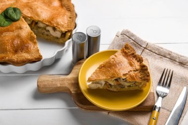 Beyaz ahşap arka planda lezzetli bir tavuklu turta ile yemek pişirme tabağı