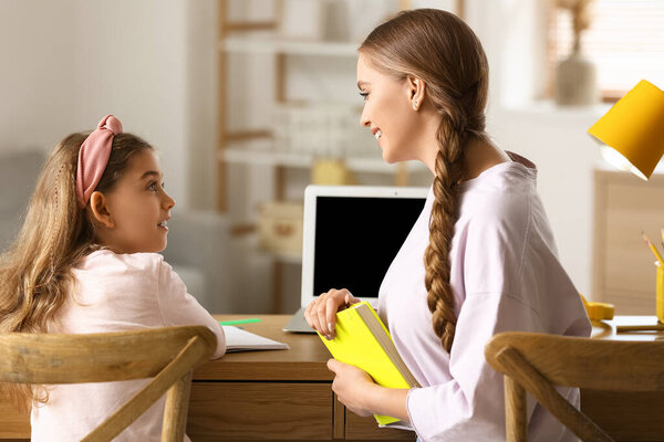 Маленькая девочка со своей матерью делает уроки дома