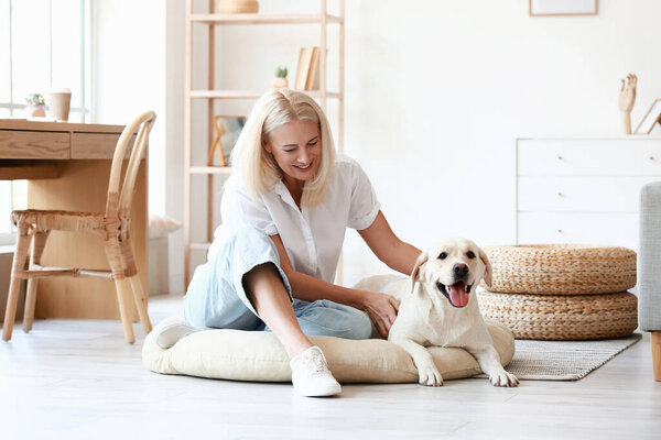 Mature woman with cute Labrador dog at home