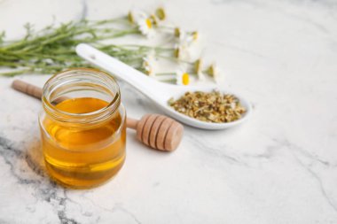 Kavanoz dolusu tatlı bal ve açık arkaplanda papatya çiçekleri