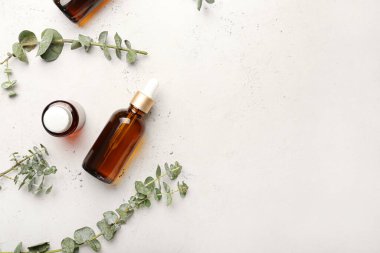 Temel yağ şişeleri ve hafif arka planda taze okaliptüs dalları