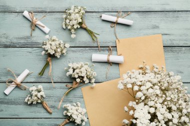 Güzel çingene çiçekleri ve renkli ahşap arka planda düğün davetiyeleri.