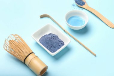 Renkli arkaplanda pudralanmış mavi kibrit çayı, chasen ve chashaku karışımı.