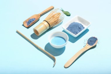 Renkli arkaplanda pudralanmış mavi kibrit çayı, chasen ve chashaku karışımı.