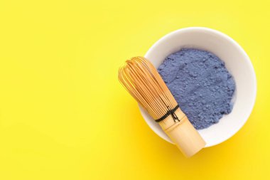 Bir kase pudra mavisi kibrit çayı ve sarı arka planda chasen.