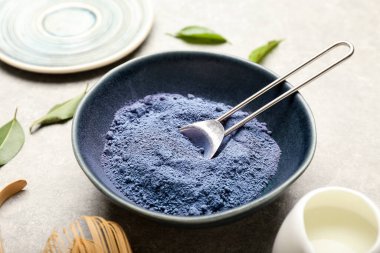 Arka planda pudralanmış mavi kibrit çaylı kase ve kaşık, yakın plan.