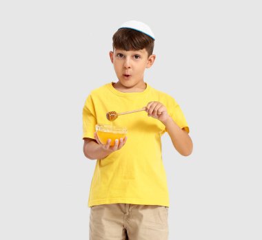 Beyaz arka planda bal olan küçük bir çocuk. Rosh Hashanah (Yahudi Yeni Yılı) kutlaması